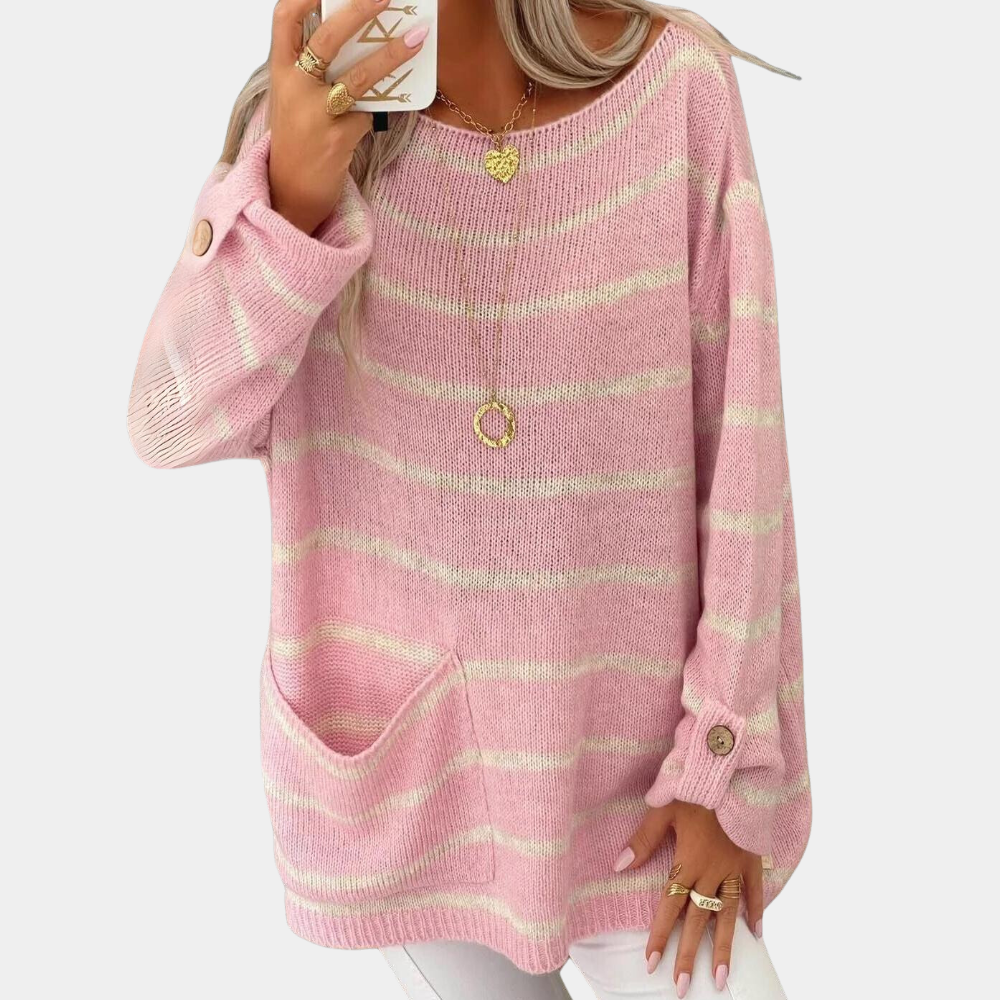 Vrouw draagt roze gestreepte trui met knopen en zak, gecombineerd met gouden sieraden. Modieuze dameskleding, casual stijl.