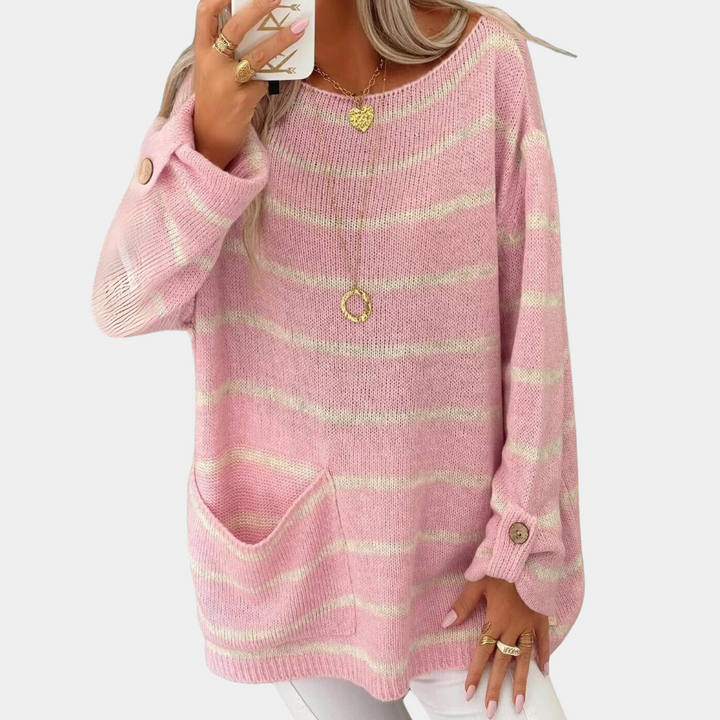 Vrouw draagt roze gestreepte trui met knopen en zak, gecombineerd met gouden sieraden. Modieuze dameskleding, casual stijl.