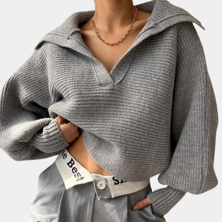 Grijze gebreide trui met wijde mouwen en diepe V-hals, gedragen door model. Modieuze dameskleding, casual stijl, herfst/winter outfit.