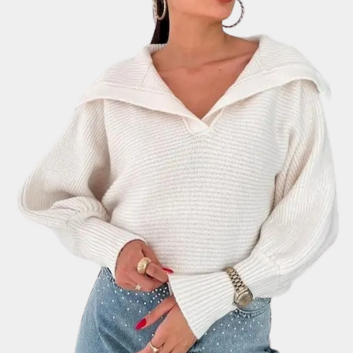 Vrouw draagt witte gebreide trui met brede kraag, gecombineerd met blauwe jeans en zilveren horloge. Modieuze dameskleding, casual stijl.