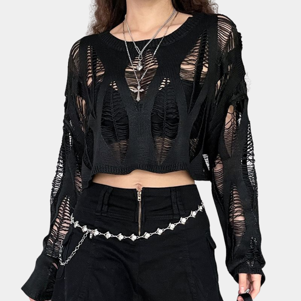 Vrouw in zwarte, gescheurde trui met lange mouwen en kettingriem. Modieuze streetwear, edgy stijl, trendy kleding voor dames.