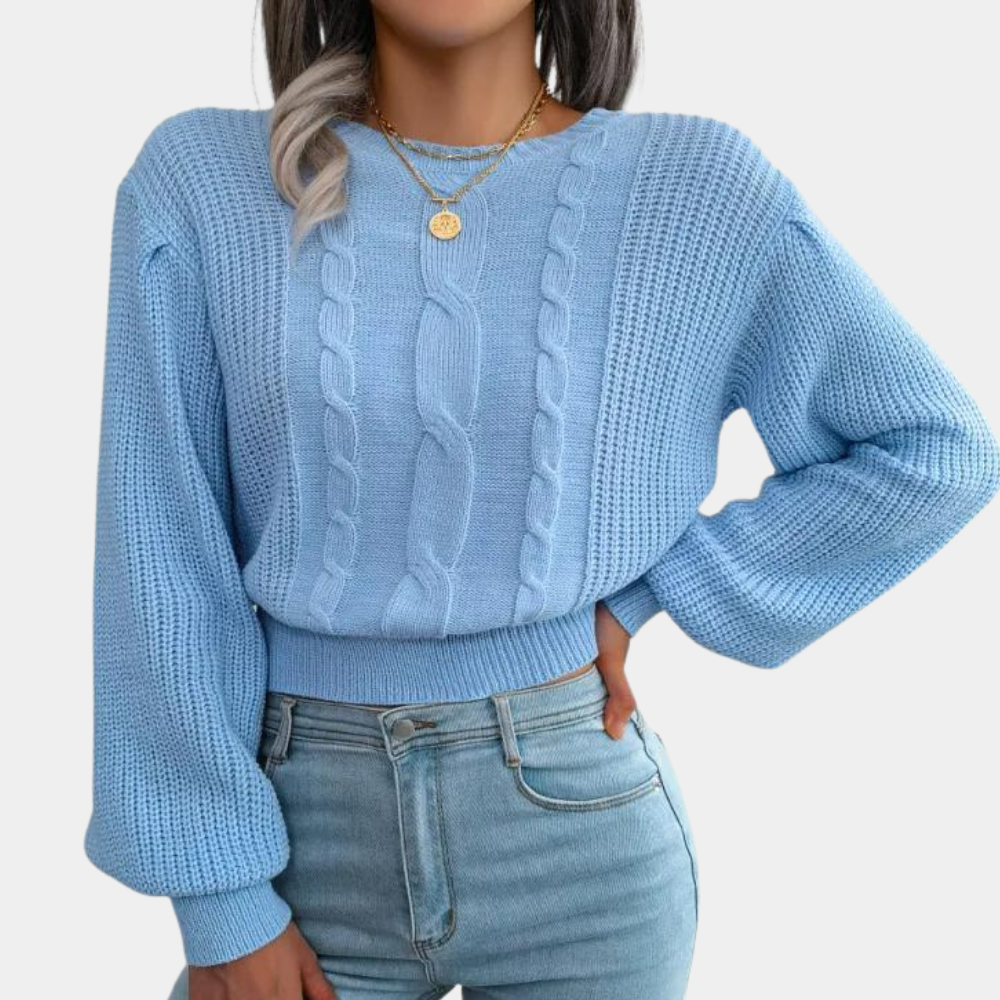 Vrouw in lichtblauwe kabeltrui met lange mouwen en gouden ketting, gecombineerd met lichtblauwe jeans. Modieuze dameskleding, casual stijl.