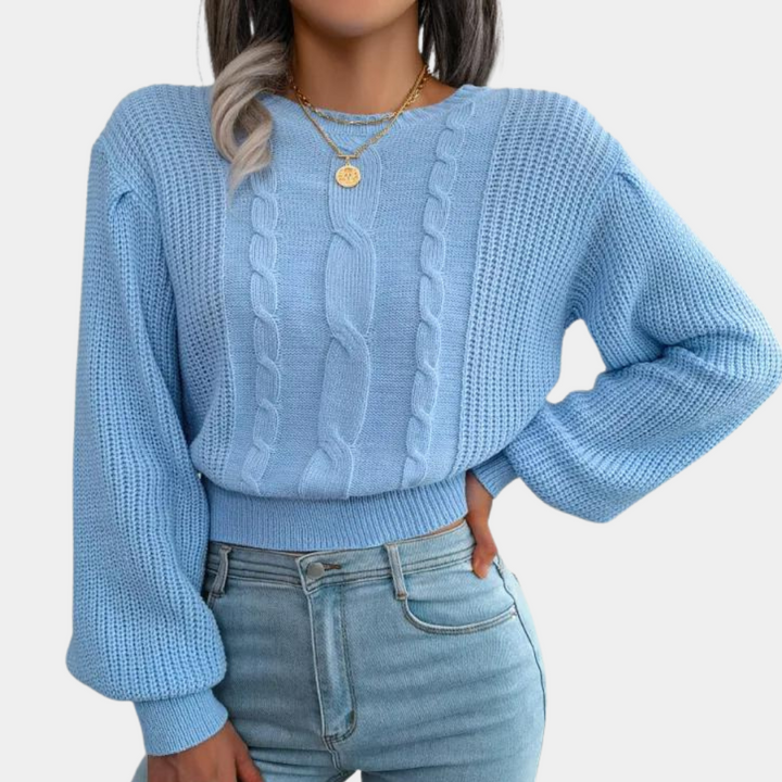 Vrouw in lichtblauwe kabeltrui met lange mouwen en gouden ketting, gecombineerd met lichtblauwe jeans. Modieuze dameskleding, casual stijl.