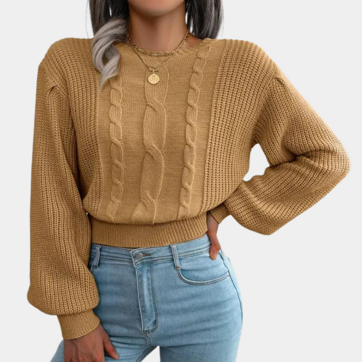 Vrouw draagt khaki kabeltrui met lange mouwen en ronde hals, gecombineerd met lichtblauwe jeans. Modieuze herfstkleding, casual stijl.