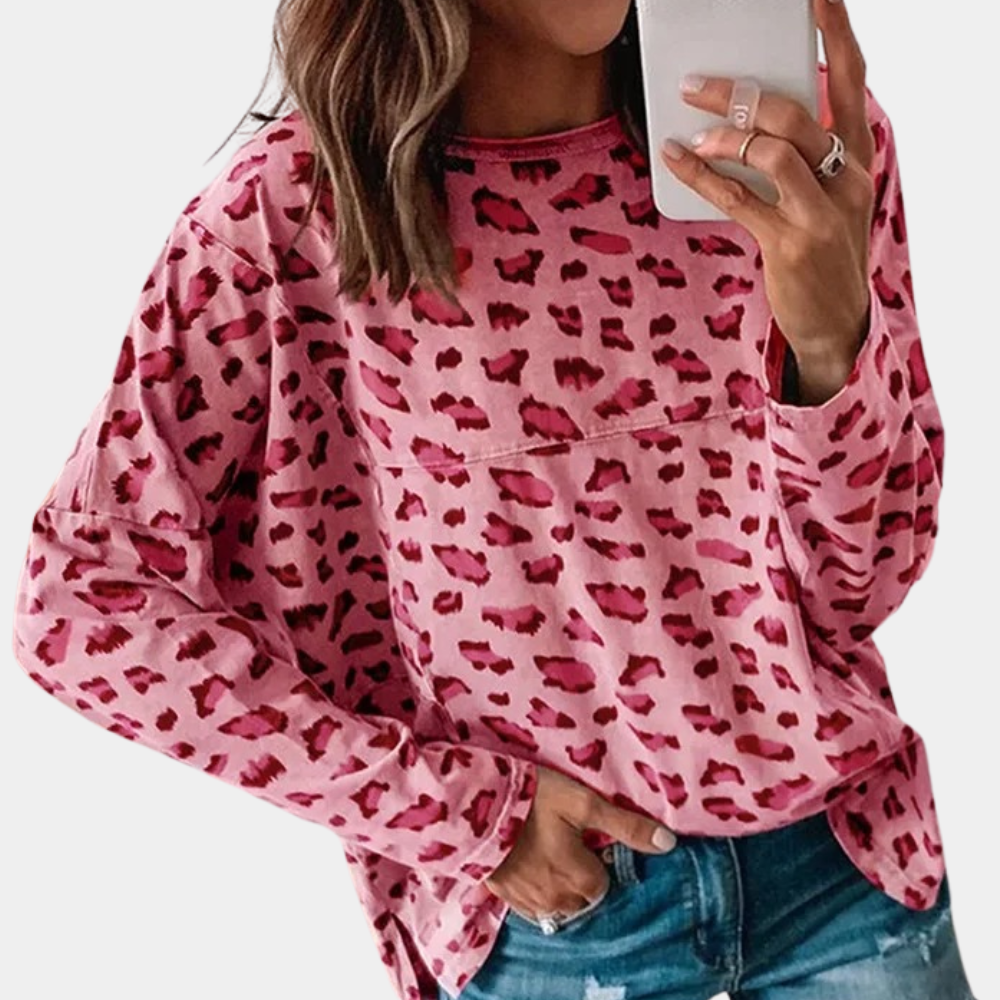 Vrouw in roze luipaardprint trui, casual mode, trendy dameskleding, selfie met smartphone, denim jeans, stijlvolle outfit.