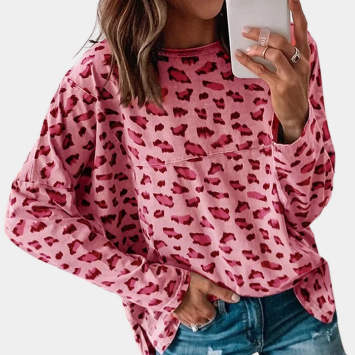 Vrouw in roze luipaardprint trui, casual mode, trendy dameskleding, selfie met smartphone, denim jeans, stijlvolle outfit.