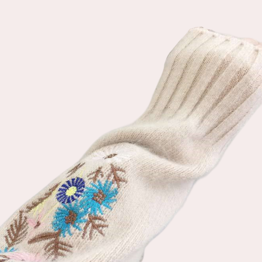 Beige gebreide trui met kleurrijk bloemenborduursel, lange mouw, ribgebreide manchetten. Modieuze dameskleding, herfst-winter stijl.