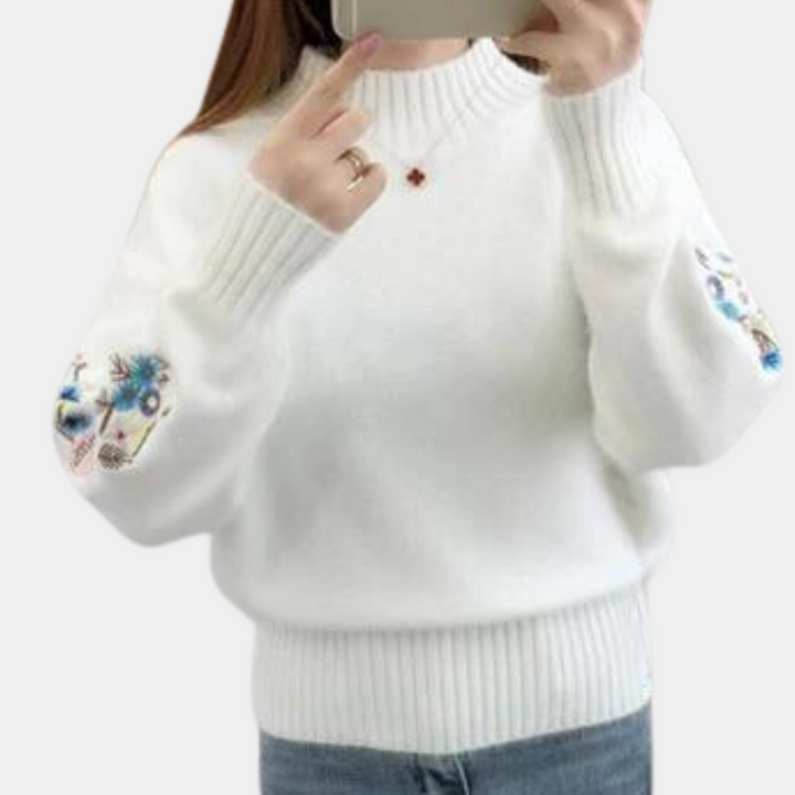 Witte trui met geborduurde bloemen op mouwen, gedragen door persoon die selfie maakt. Modieuze dameskleding, casual stijl, wintermode.