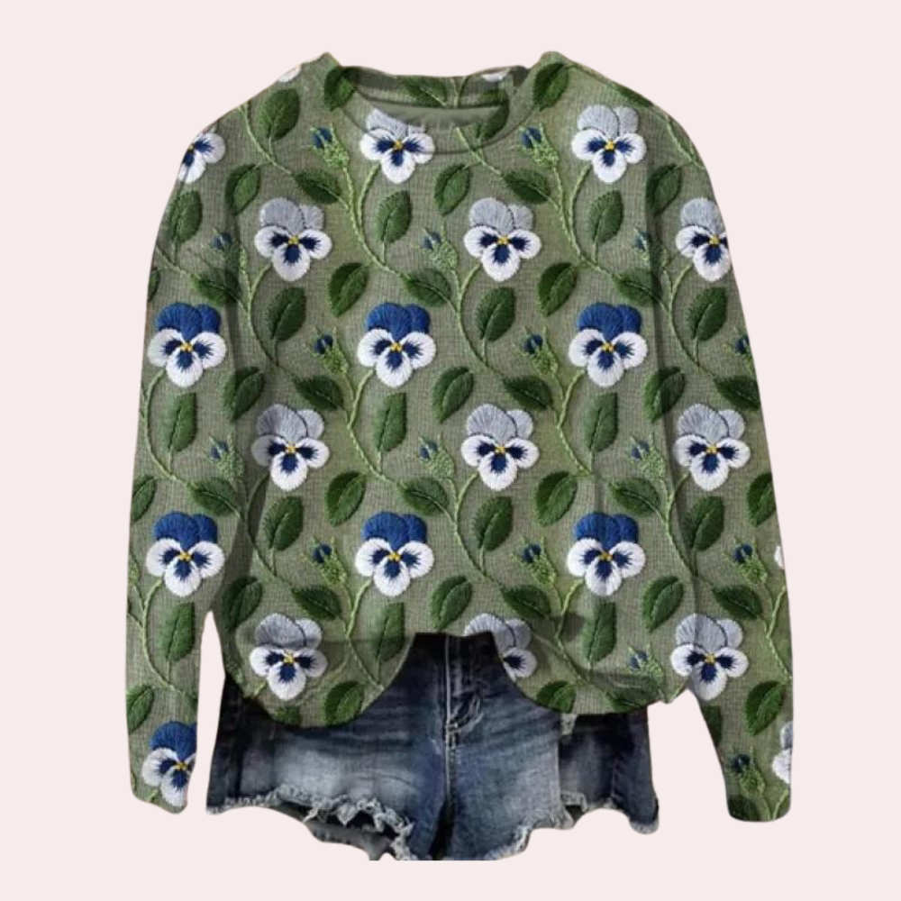 Groene trui met viooltjespatroon, lange mouwen, gecombineerd met denim shorts. Trendy damesmode, casual outfit, bloemenprint.