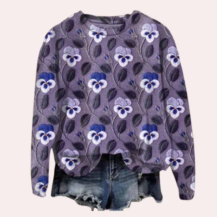 Paarse bloemenblouse met lange mouwen en blauw-witte bloemenprint, gecombineerd met denim shorts. Trendy damesmode, casual outfit.