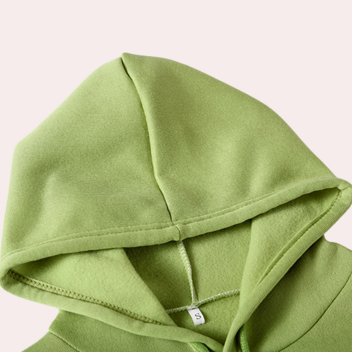 Lichtgroene hoodie met capuchon, close-up van de stof en naden, maatlabel zichtbaar. Comfortabele katoenen trui, trendy streetwear mode.