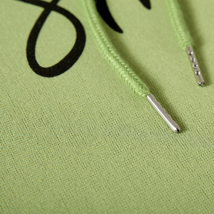 Close-up van groene hoodie met zwarte opdruk en groene trekkoorden. Modieuze streetwear, comfortabele katoenen stof. Perfect voor casual outfits.