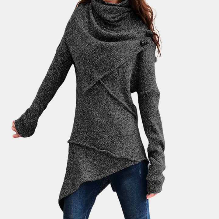 Zwarte asymmetrische damestrui met lange mouwen en col, gecombineerd met blauwe jeans. Modieuze winterkleding, comfortabele pasvorm.