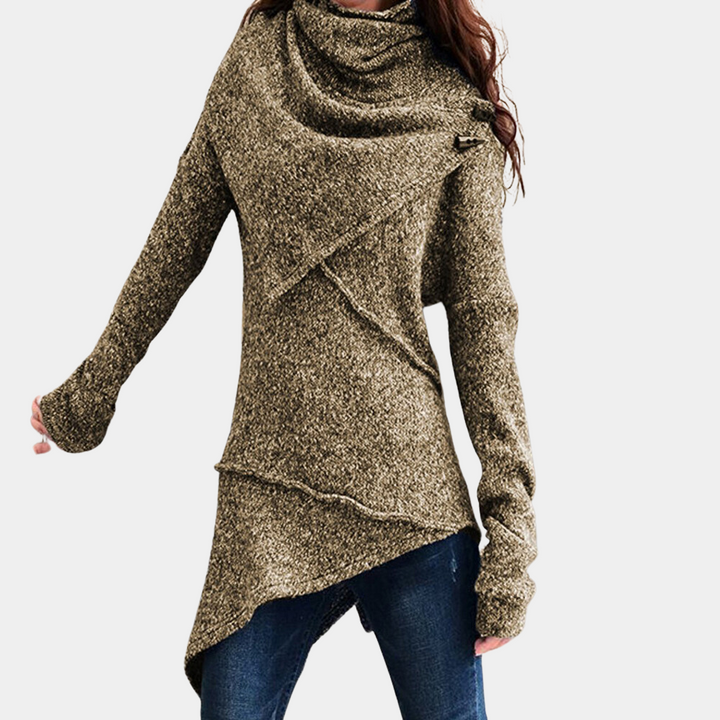 Vrouw draagt asymmetrische khaki trui met lange mouwen en sjaalkraag, gecombineerd met blauwe jeans. Modieuze dameskleding, herfststijl.