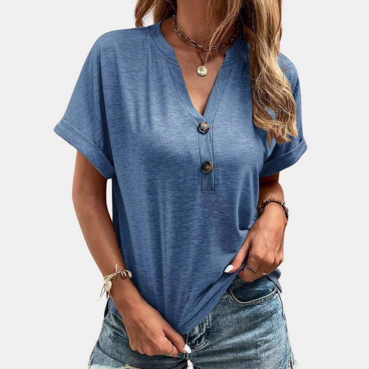 Blauwe dames T-shirt met korte mouwen, V-hals en knoopsluiting, gedragen met spijkerbroek. Perfect voor casual zomeroutfits.