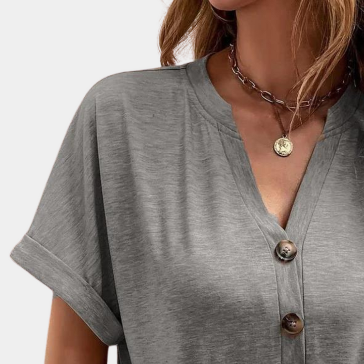 Grijze damesblouse met korte mouwen en knoopsluiting, gedragen door model. Trendy casual kleding, ideaal voor dagelijks gebruik.