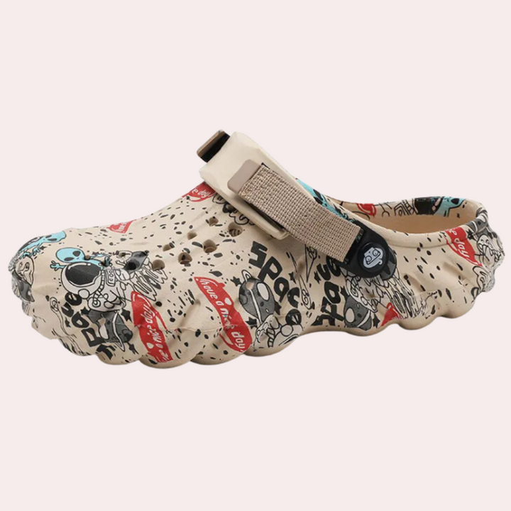 Beige klomp met cartoonprint, verstelbare band en perforaties, ideaal voor casual gebruik. Comfortabele en modieuze unisex schoenen.