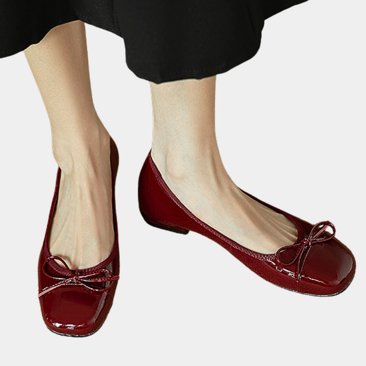 Rode lakleren ballerina's met strikdetail, gedragen door vrouw. Elegante platte schoenen, perfect voor casual en formele outfits.