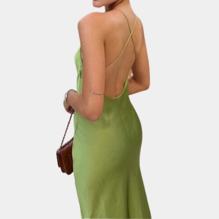 Groene satijnen jurk met open rug en dunne bandjes, gedragen door vrouw. Elegante avondjurk, perfect voor zomerse gelegenheden.