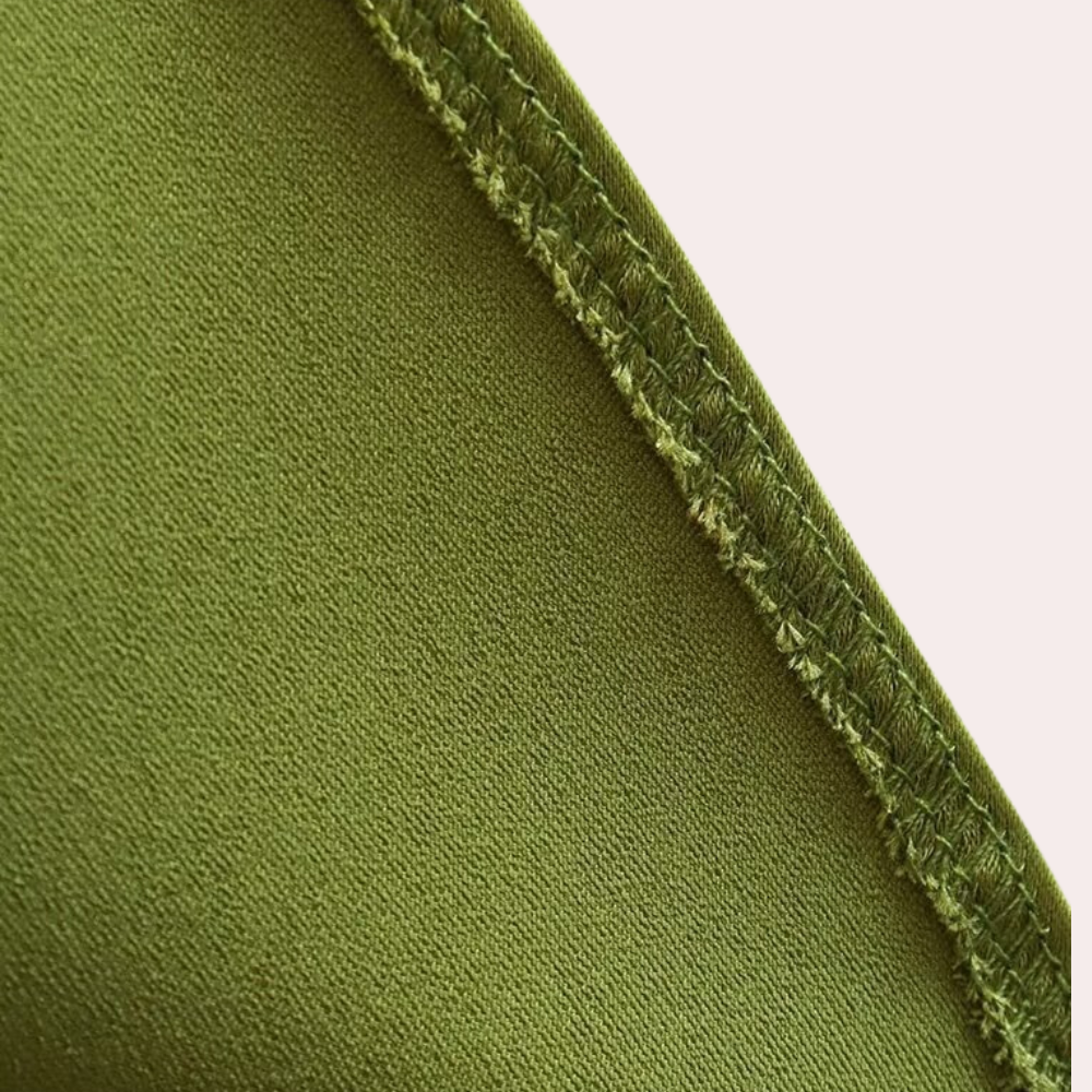 Groene stof close-up met zichtbare stiksels, textieltextuur, naad details. Perfect voor modeontwerp, kledingproductie, duurzame stoffen.