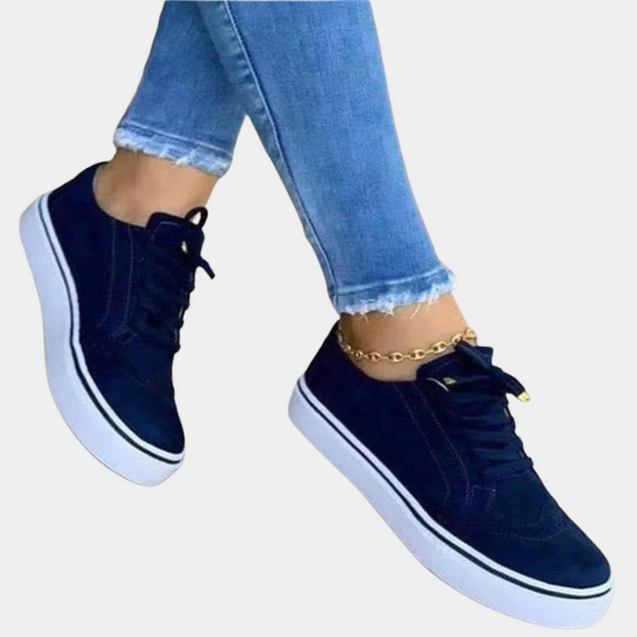 Blauwe sneakers met witte zolen, gedragen met lichtblauwe jeans en enkelbandje. Modieuze dames schoenen, casual stijl, comfortabele pasvorm.