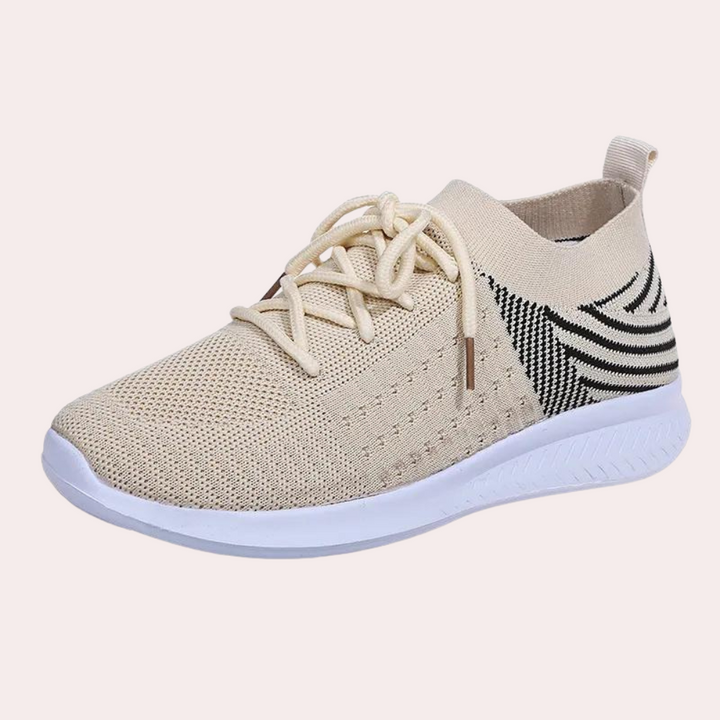 Beige gebreide sneaker met witte zool en zwarte strepen, ademend en lichtgewicht, ideaal voor casual en sportief gebruik.