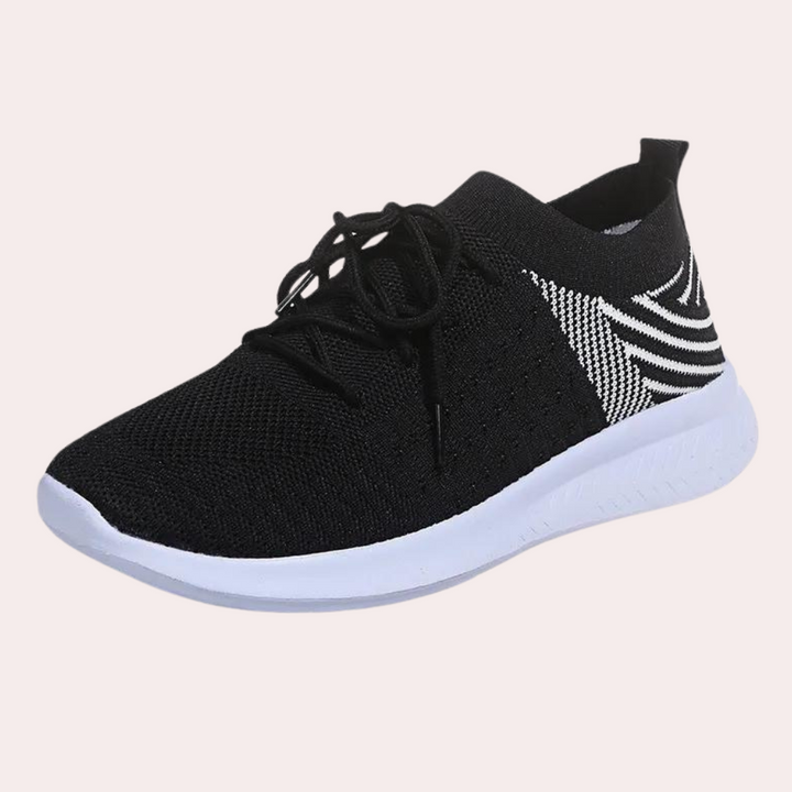 Zwarte sportschoen met witte zool en gestreept patroon, ademend mesh materiaal, ideaal voor hardlopen en casual gebruik.