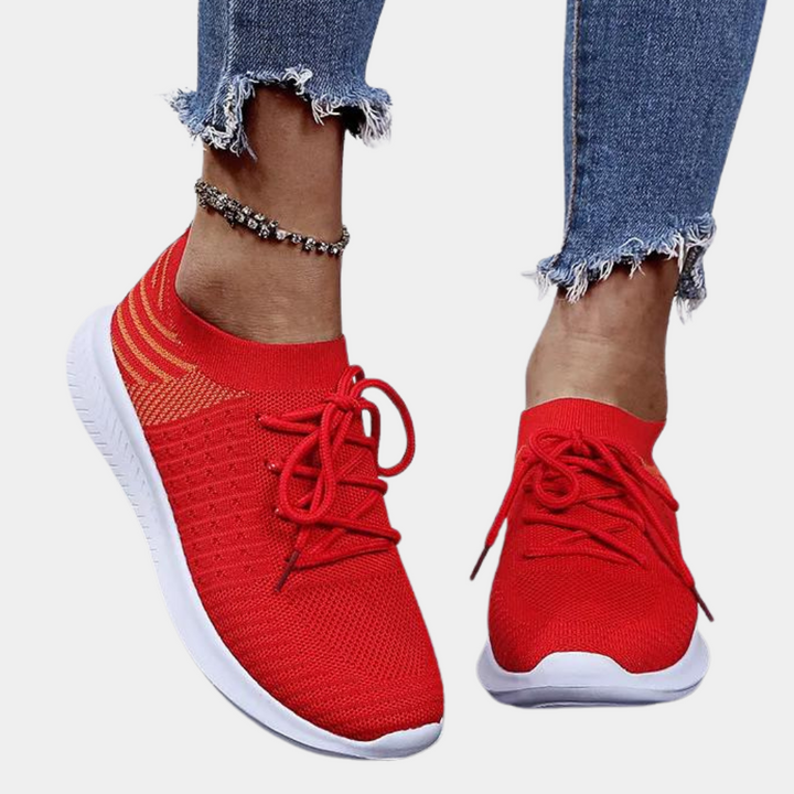 Rode sneakers met witte zool, gebreid bovenwerk en veters, gedragen met gerafelde jeans. Comfortabele damesmode, casual schoenen.