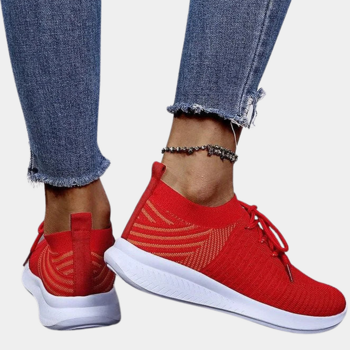 Rode sneakers met witte zool, gedragen met blauwe jeans. Moderne sportschoenen, ademend materiaal, casual stijl, geschikt voor dagelijks gebruik.