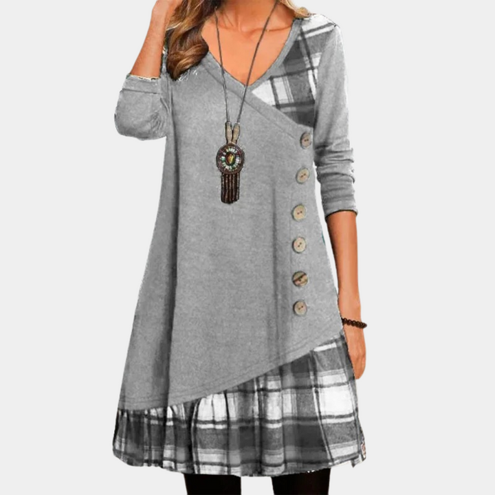 Grijze damesjurk met asymmetrische knopen en geruite details, lange mouwen, V-hals. Modieuze casual outfit, perfect voor herfst en winter.