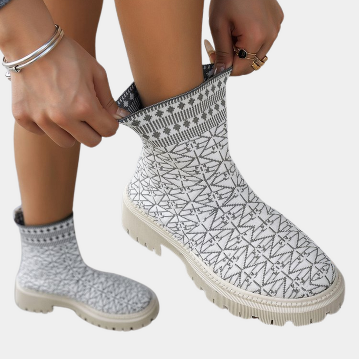 Witte gebreide enkellaars met geometrisch patroon, dikke zool en elastische schacht. Trendy damesmode, comfortabele winterlaars.