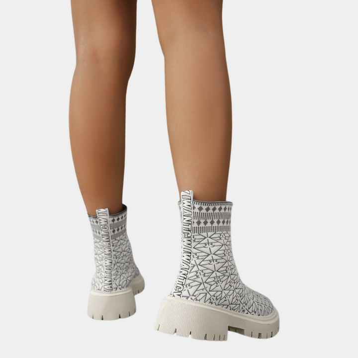 Witte enkellaarsjes met zwart geometrisch patroon, dikke zool en elastische inzet. Modieuze dameslaarzen, trendy schoenen, comfortabele pasvorm.