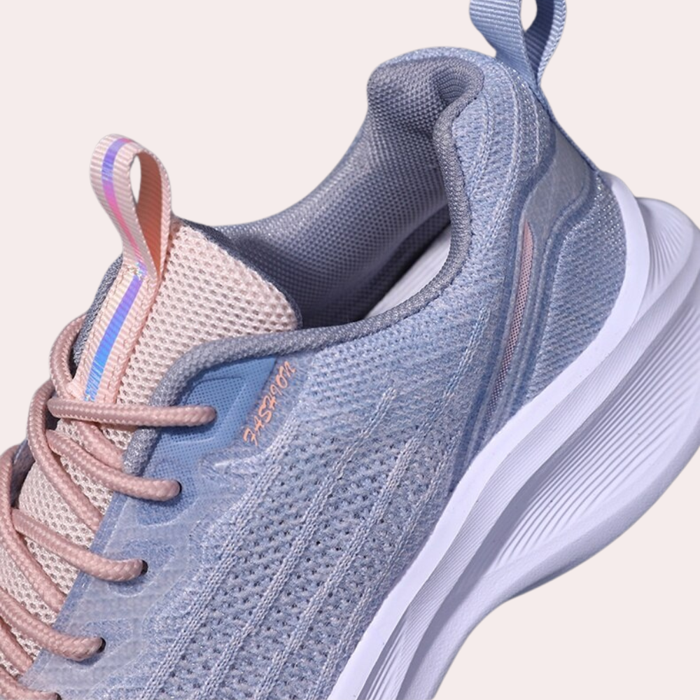 Grijze sportschoen met roze en blauwe accenten, ademend mesh bovenwerk, witte zool en lusdetail. Perfect voor hardlopen en casual gebruik.