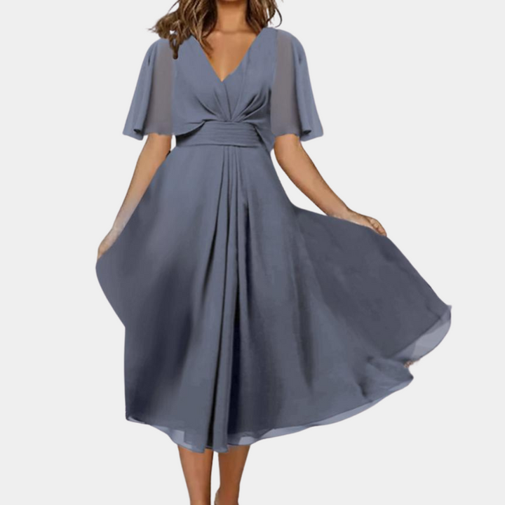 Vrouw in elegante blauwe jurk met V-hals en wijde mouwen, vloeiende rok. Perfect voor avondkleding, formele evenementen, modieuze dameskleding.