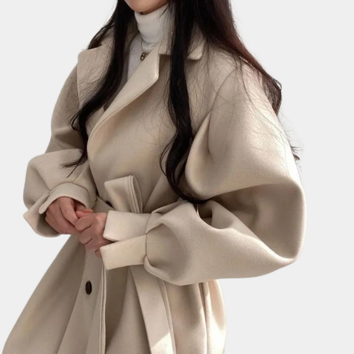 Vrouw in stijlvolle beige wollen jas met ceintuur, modieuze ballonmouwen en witte coltrui. Trendy damesmode, herfst-winter outfit.