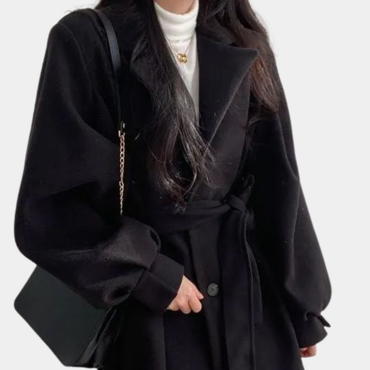 Vrouw in zwarte wollen jas met riem, witte coltrui en zwarte schoudertas. Modieuze winterkleding, elegant en stijlvol design.