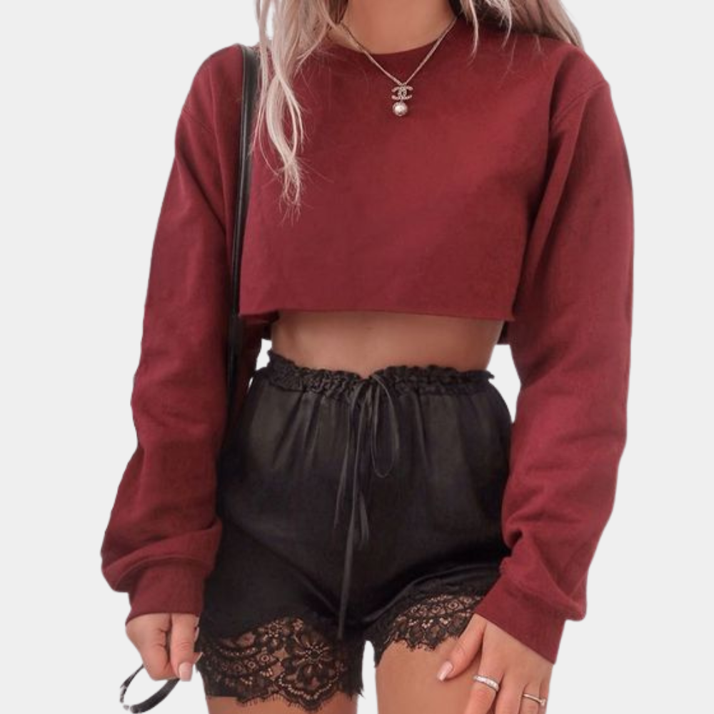 Vrouw in bordeauxrode cropped trui en zwarte kanten shorts. Trendy damesmode, herfstoutfit, casual streetwear.