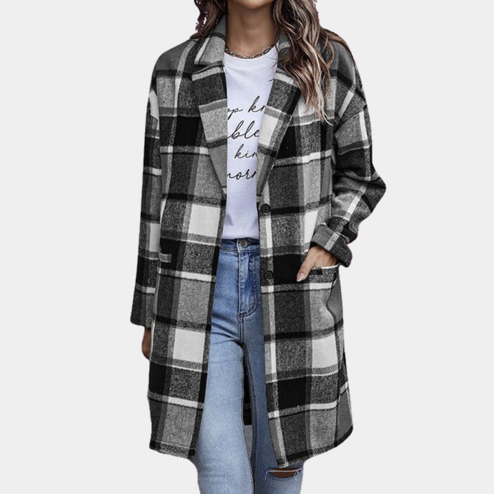 Grijze geruite damesjas, lange mouwen, knoopsluiting, casual stijl, gedragen over een wit T-shirt en blauwe jeans. Perfect voor herfstmode.