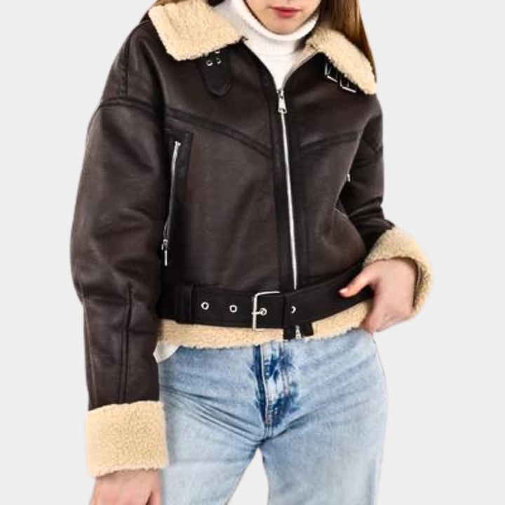 Vrouw in bruine leren jas met schapenvacht kraag en manchetten, witte trui en blauwe jeans. Modieuze winterkleding, damesmode.