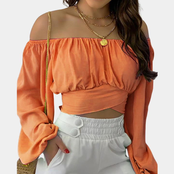 Oranje off-shoulder top met lange mouwen, gedragen door vrouw. Trendy damesmode, casual zomeroutfit, stijlvolle kleding.