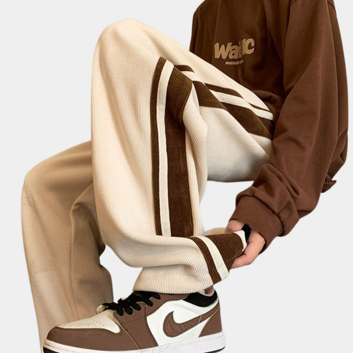 Beige corduroy broek met bruine strepen, gedragen met bruine en witte sneakers en een bruine trui. Trendy streetwear mode voor heren.