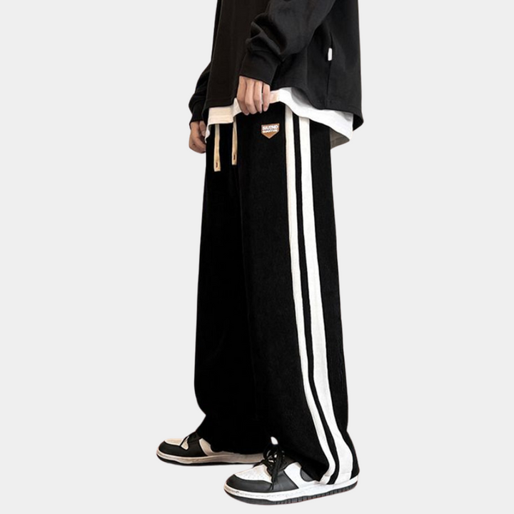 Zwarte joggingbroek met witte strepen, casual streetwear stijl, unisex ontwerp, comfortabele pasvorm, ideaal voor dagelijks gebruik en sportieve activiteiten.
