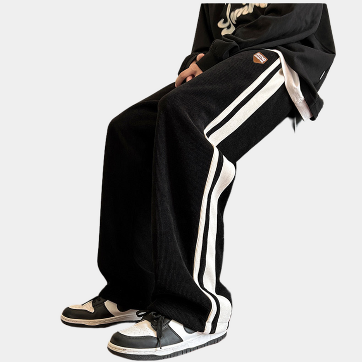 Zwarte joggingbroek met witte strepen, gedragen door persoon. Streetwear mode, comfortabele pasvorm, casual stijl, trendy sportkleding.