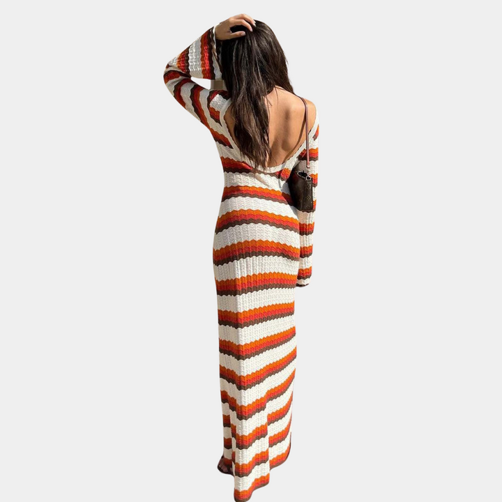 Vrouw in lange, gebreide jurk met oranje en witte strepen, open rug. Modieuze dameskleding, herfststijl, casual chique outfit.