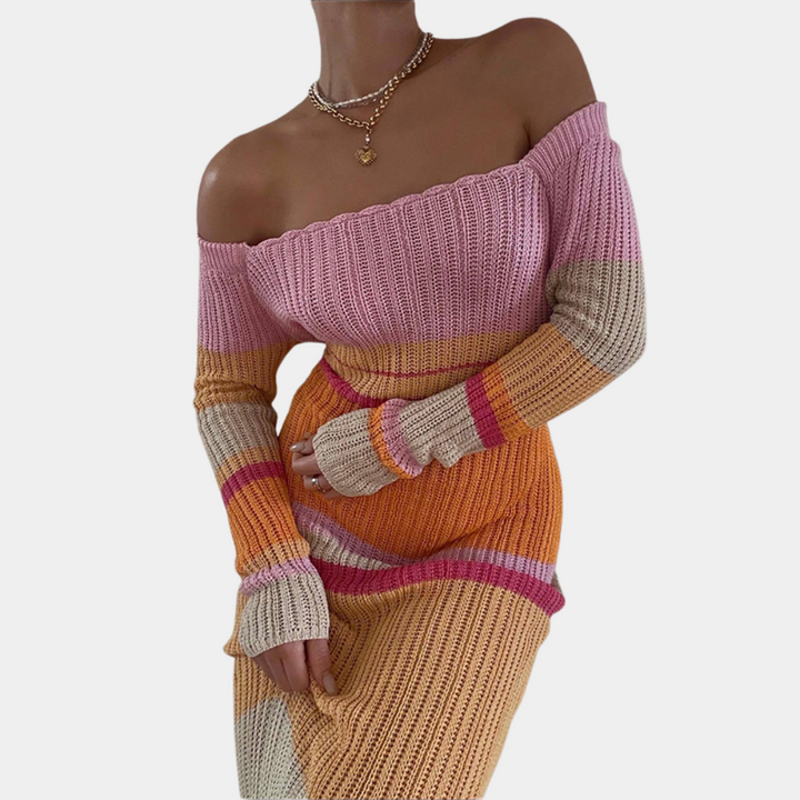 Vrouw in off-shoulder gebreide jurk met roze, oranje en beige strepen. Trendy damesmode, herfstkleding, stijlvolle gebreide jurk.
