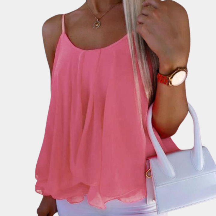 Vrouw in roze chiffon top met dunne bandjes, witte tas en horloge. Trendy zomermode, casual dameskleding, stijlvolle outfit.