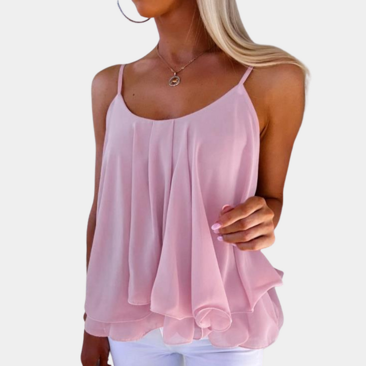 Vrouw in lichtroze, mouwloze chiffon top met spaghettibandjes, perfect voor zomermode. Elegante en luchtige damesblouse.