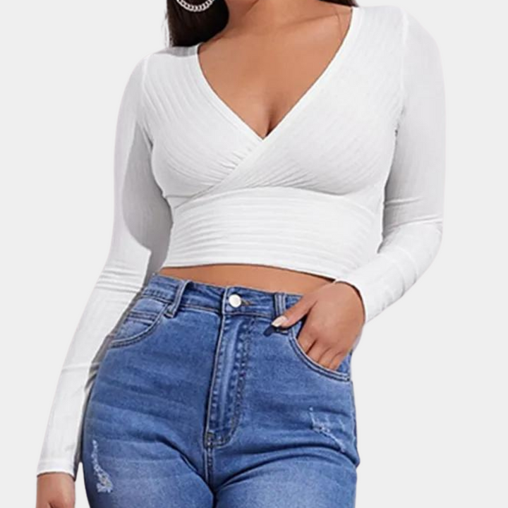 Vrouw in witte, lange mouwen crop top met V-hals en blauwe high-waist jeans. Modieuze dameskleding, casual outfit, trendy stijl.