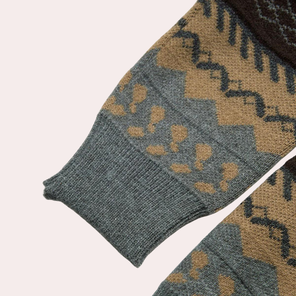 Grijze wollen trui met bruin en zwart zigzagpatroon, close-up van mouw. Warme winterkleding, Scandinavisch design, comfortabele gebreide stof.