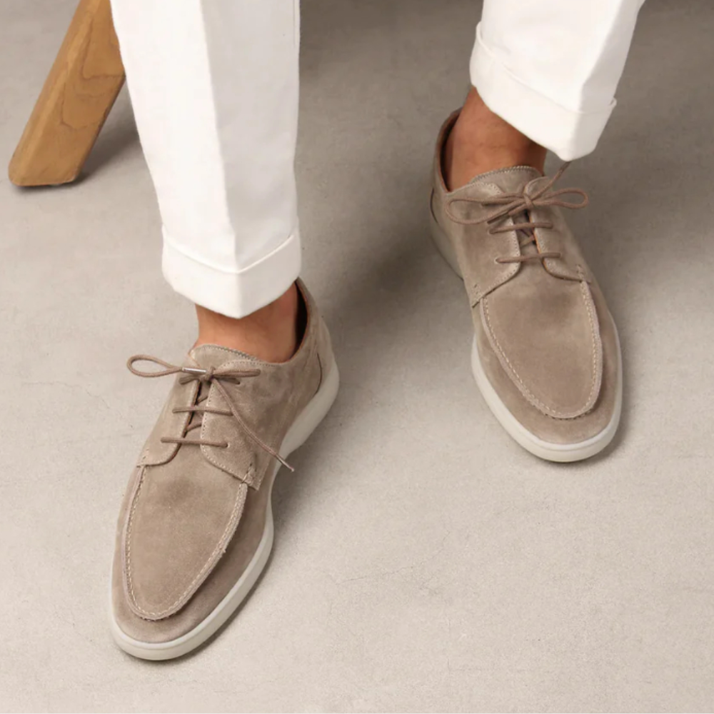 Beige suède herenschoenen, Vilano model, met veters en witte zool, gedragen met witte broek. Stijlvolle casual schoenen voor herenmode.